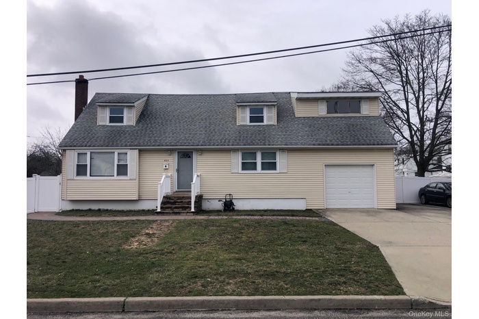 View of front of home featuring driveway, a shingled roof, a chimney, and a garage