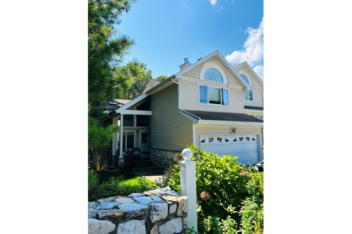 View of side of home featuring an attached garage and stone siding