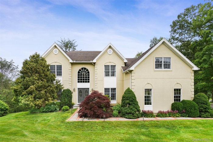 View of front of property featuring stucco siding, a front yard, and a shingled roof