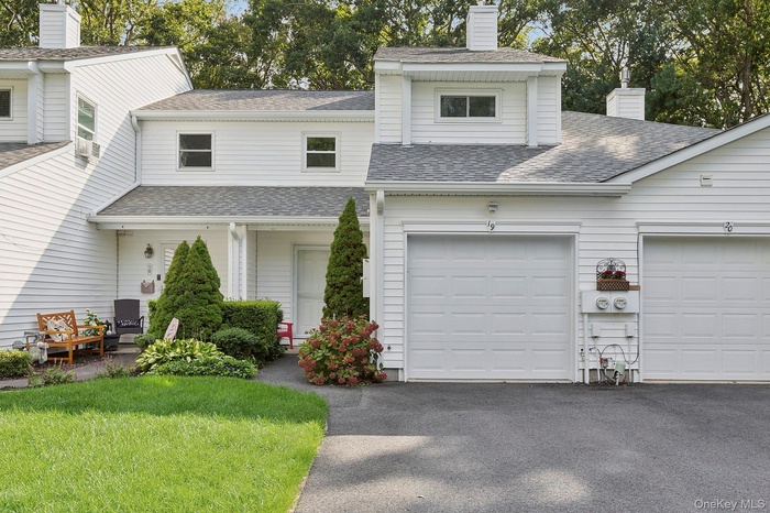 Traditional home featuring a shingled roof, a chimney, and driveway