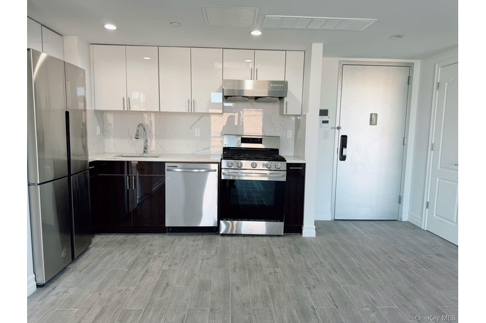 Kitchen featuring a sink, tasteful backsplash, under cabinet range hood, stainless steel appliances, and visible vents