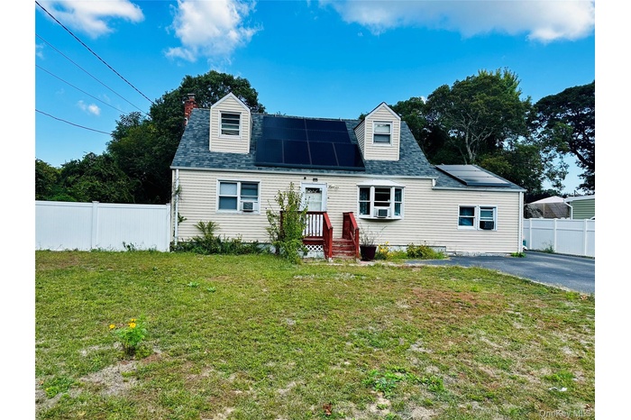 New england style home featuring solar panels, a chimney, and a shingled roof