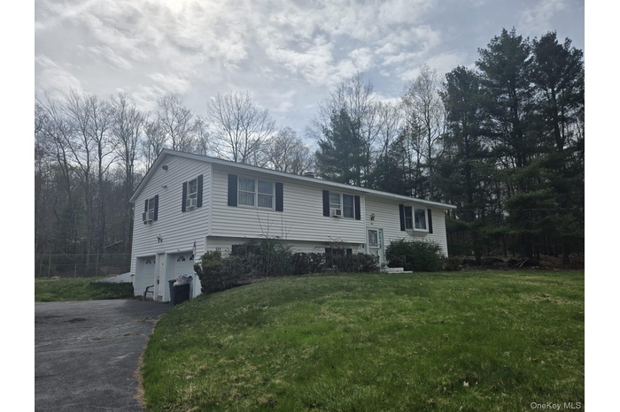 Raised ranch featuring a front yard, driveway, and an attached garage