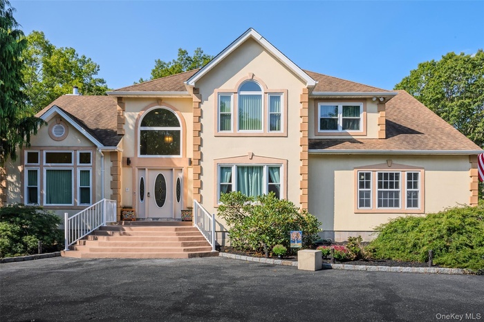 View of front facade featuring a shingled roof and stucco siding