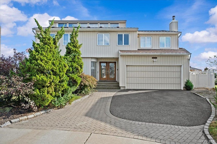 Traditional-style home featuring decorative driveway, french doors, a chimney, and a garage