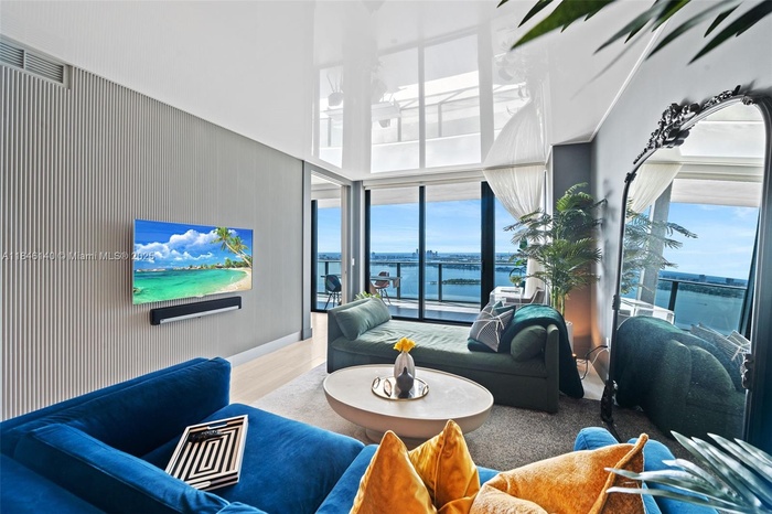 Living Area with unobstructed Bay, Port and Edgewater Skyline Views. Custom finishes include ribbed custom wall with built in HD TV, Custom reflective