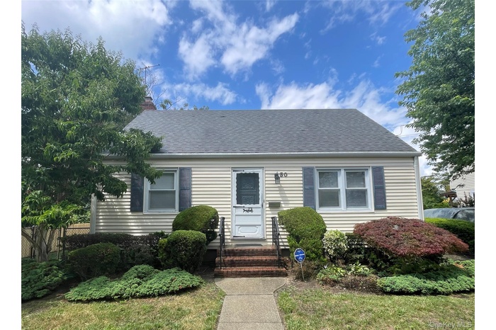 View of front of home with a shingled roof and a chimney