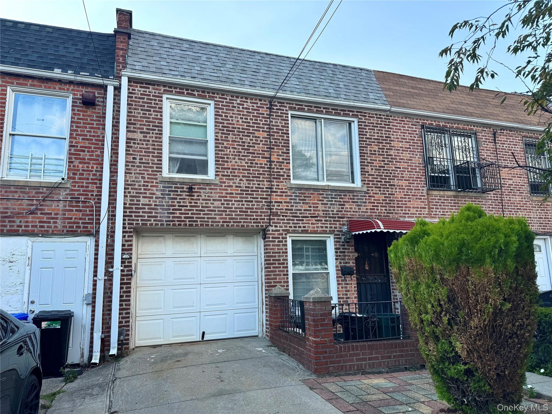 View of front of home - roof, brick siding, driveway, and a garage