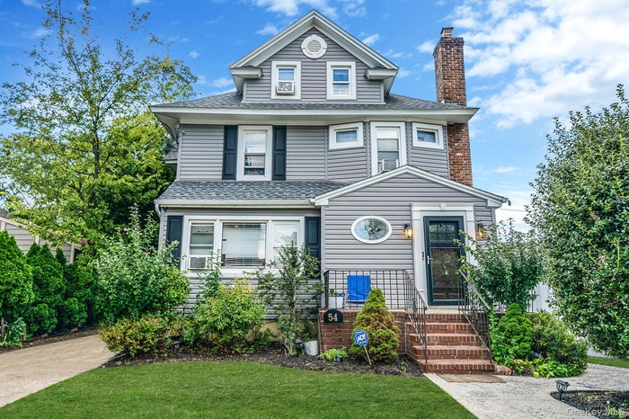 American foursquare style home with a chimney, roof with shingles, and a front yard