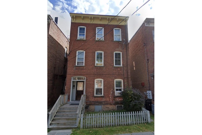 View of front of property featuring brick siding and a fenced front yard