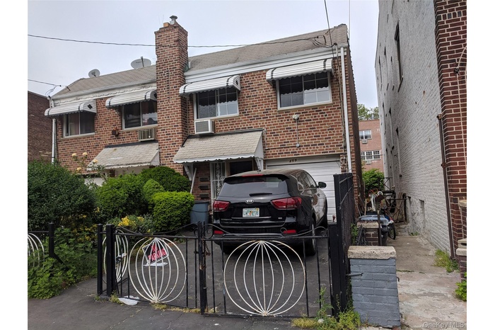 View of front facade featuring a gate, a chimney, brick siding, and roof with shingles