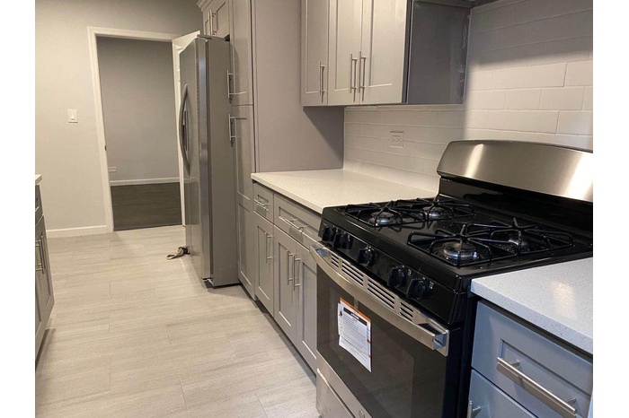 Kitchen featuring stainless steel appliances, gray cabinetry, light countertops, and decorative backsplash