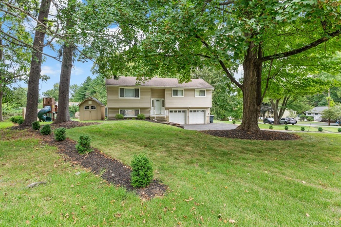 Raised ranch with driveway, a garage, a front yard, and a storage unit