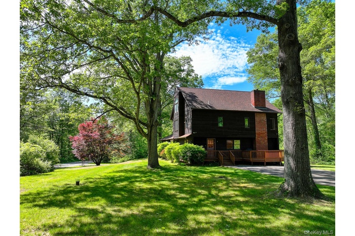 View of front of house featuring a chimney, a front yard, and a wooden deck