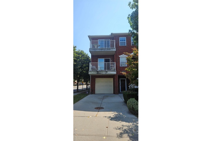 Traditional-style home featuring a balcony, concrete driveway, a garage, and brick siding