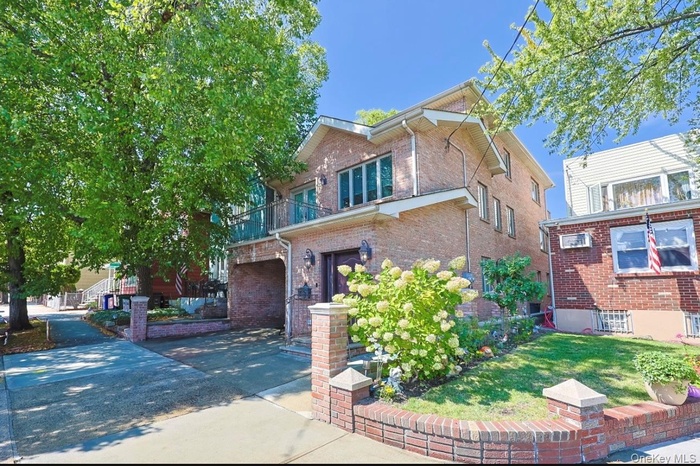 View of front of house featuring brick siding, a balcony, a front yard, and concrete driveway