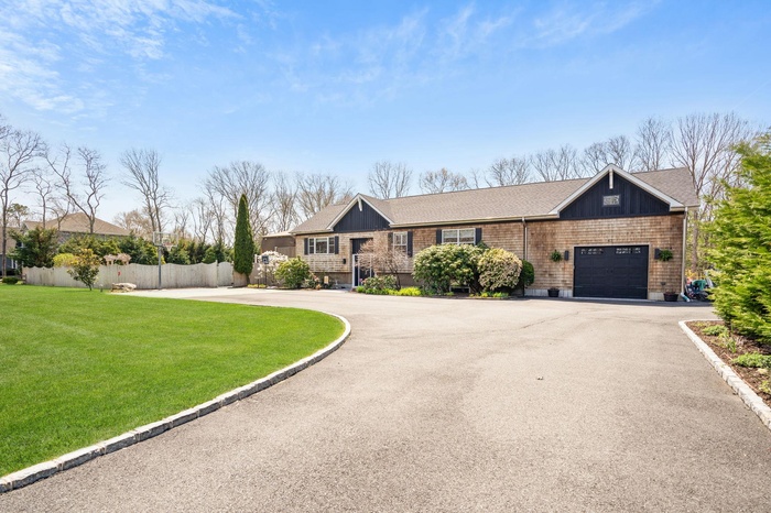 Ranch-style house featuring a front yard, a garage