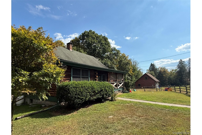Back of house featuring log exterior, a chimney, and roof with shingles