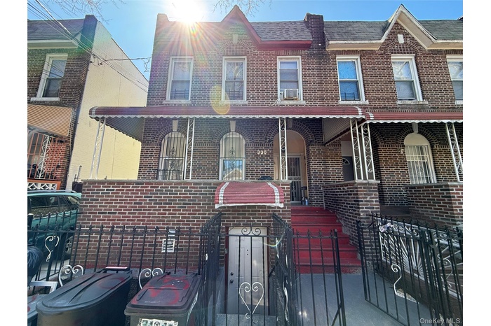 View of property featuring a fenced front yard, covered porch, and brick siding