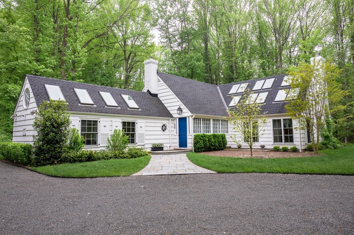 View of front of home featuring a chimney, a shingled roof, and a front lawn