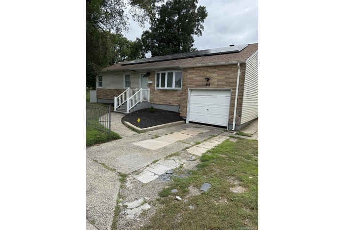 Ranch-style home with stone siding, solar panels, and an attached garage