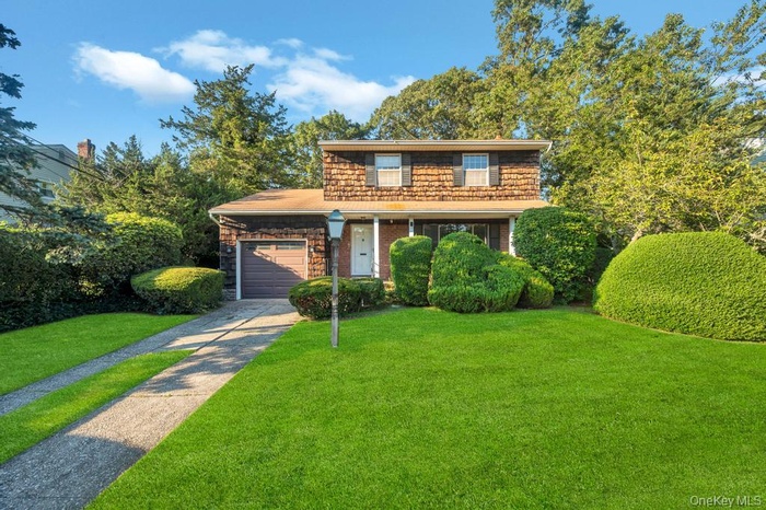View of front of property with a front yard, concrete driveway, and an attached garage