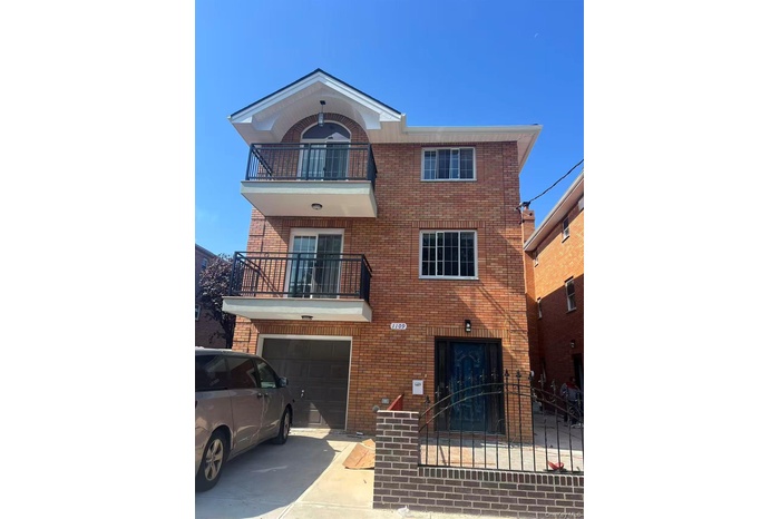 View of front facade with a balcony, brick siding, concrete driveway, and an attached garage