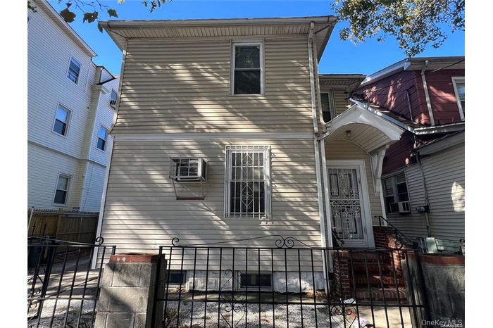 Traditional-style house with cooling unit, an AC wall unit, and a fenced front yard