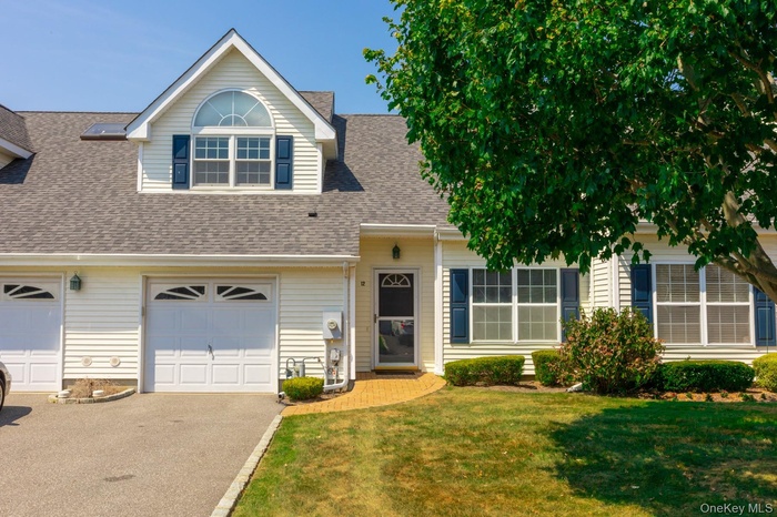 View of front of property with driveway, a front lawn, a shingled roof, and a garage