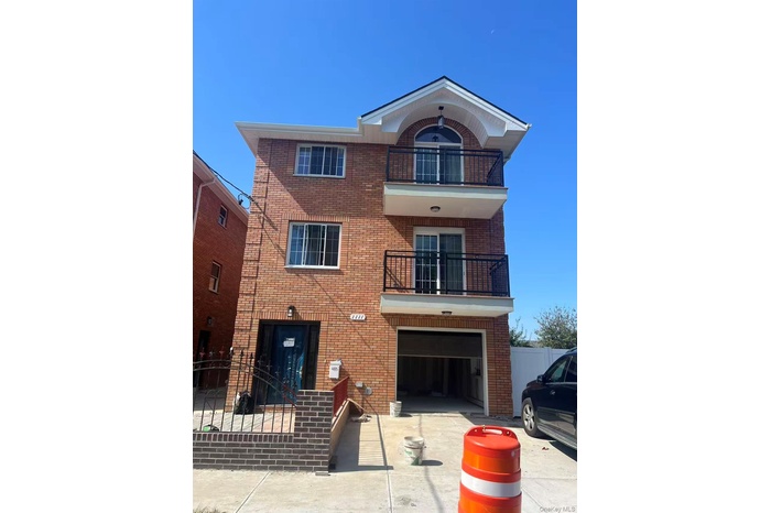 View of front of property with a balcony, brick siding, and driveway