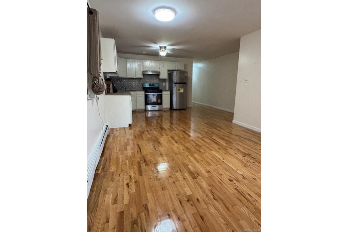 Kitchen featuring freestanding refrigerator, a baseboard heating unit, light wood-style flooring, and electric range