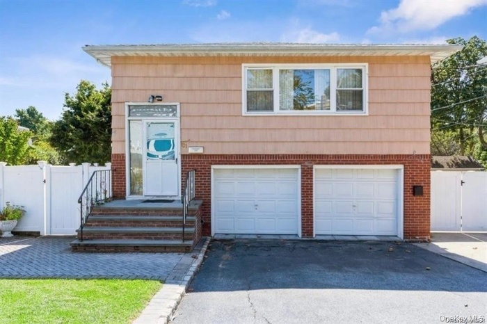 View of front of property featuring a gate, a garage, asphalt driveway, and brick siding