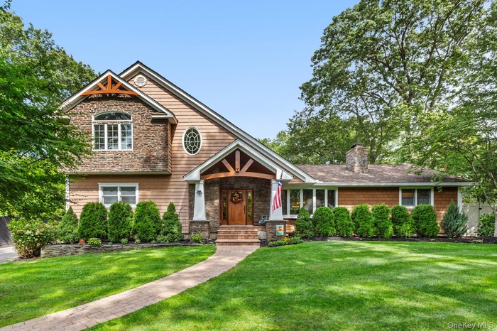 Craftsman-style house with a front lawn, stone siding, and a chimney