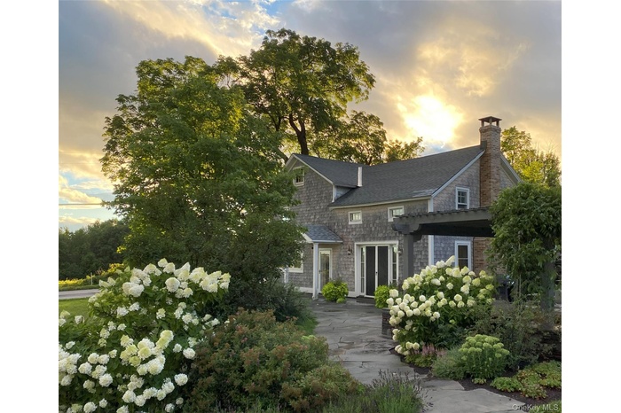 View of front of home featuring a chimney and a shingled roof