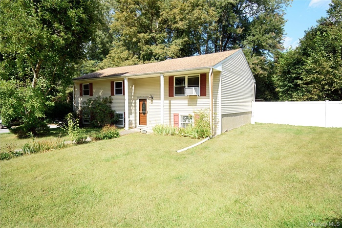 Split foyer home with view of wooded area and a shingled roof