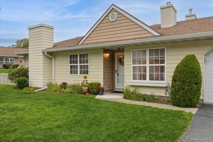 View of front of property featuring a chimney, a shingled roof, and a front yard