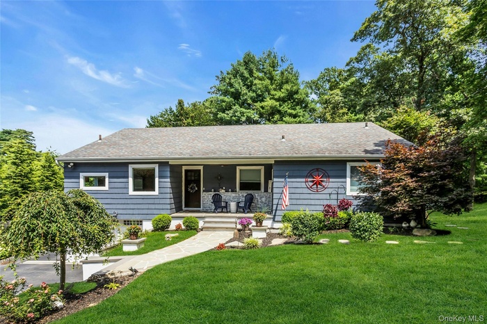 Ranch-style house featuring a porch, roof with shingles, and a front yard