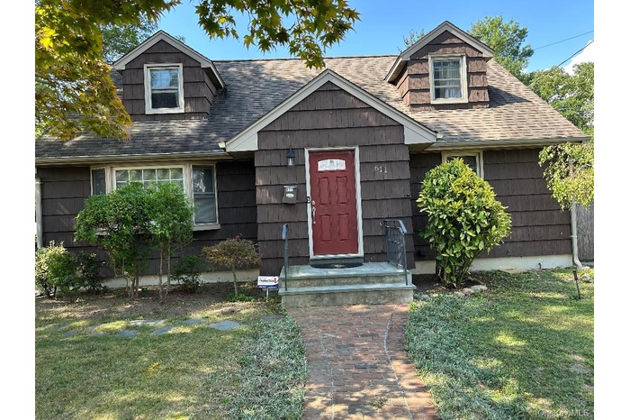 View of front of property with roof with shingles and a front yard