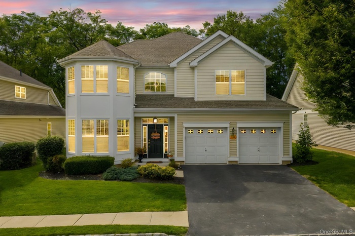 View of front of home featuring roof with shingles, a front lawn, an attached garage, and driveway