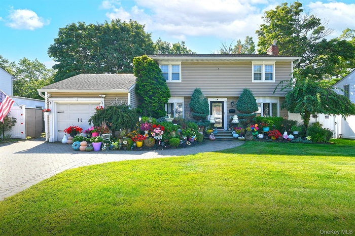 Colonial house featuring a garage, a chimney, and decorative driveway
