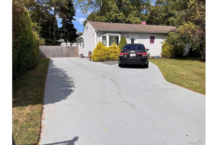 View of side of home with driveway, a chimney, and roof with shingles