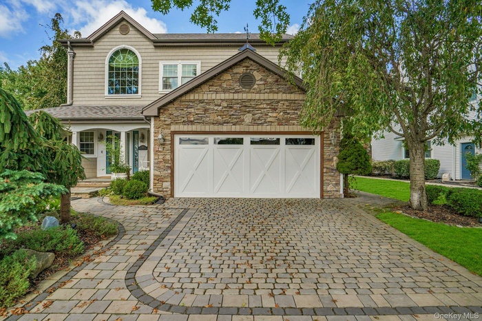 Craftsman inspired home with stone siding, decorative driveway, a porch, and an attached garage