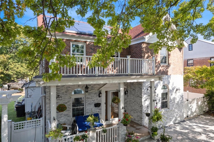 Rear view of house with brick siding, a balcony, and roof mounted solar panels