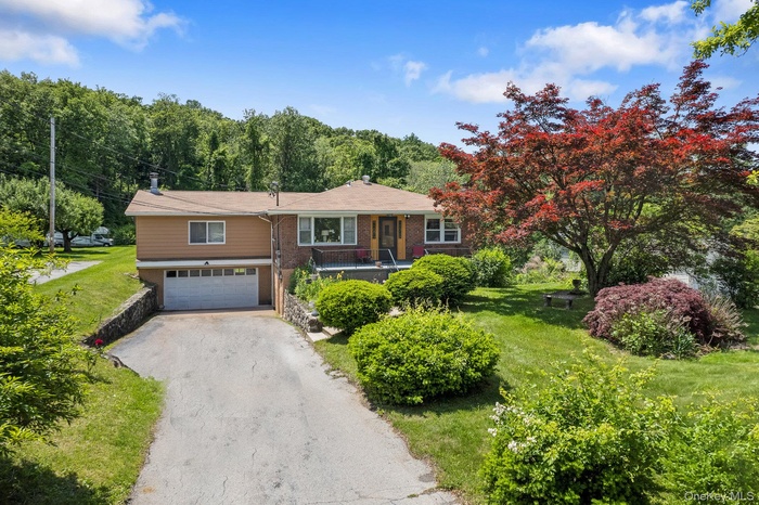 Ranch-style house featuring a garage, asphalt driveway, and a front yard