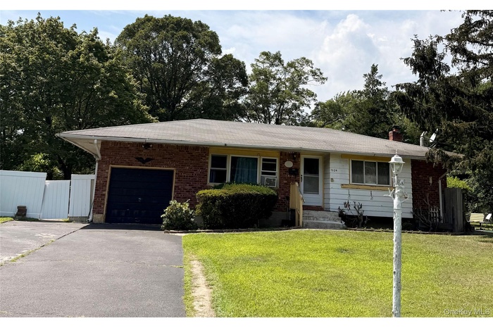 Single story home with driveway, brick siding, an attached garage, and a chimney