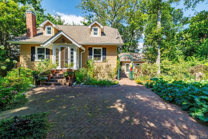 View of front of home with roof with shingles, covered porch, and a chimney