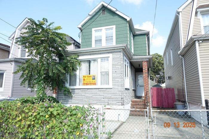 View of front of house featuring a gate, a fenced front yard, and brick siding