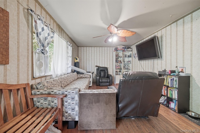 Living area with wood finished floors, wallpapered walls, and ceiling fan