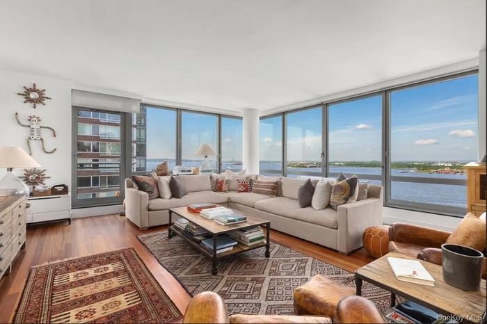 Living area featuring wood finished floors, a water view, and a wall of windows