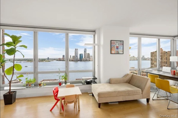 Sitting room with a water view, a view of skyline, light wood-style flooring, and a desk